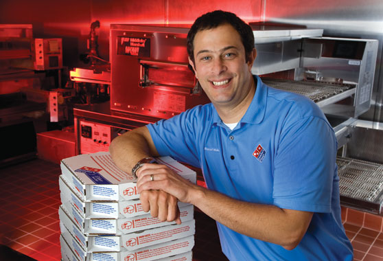 Image of Russell Weiner leaning on a stack of pizza boxes