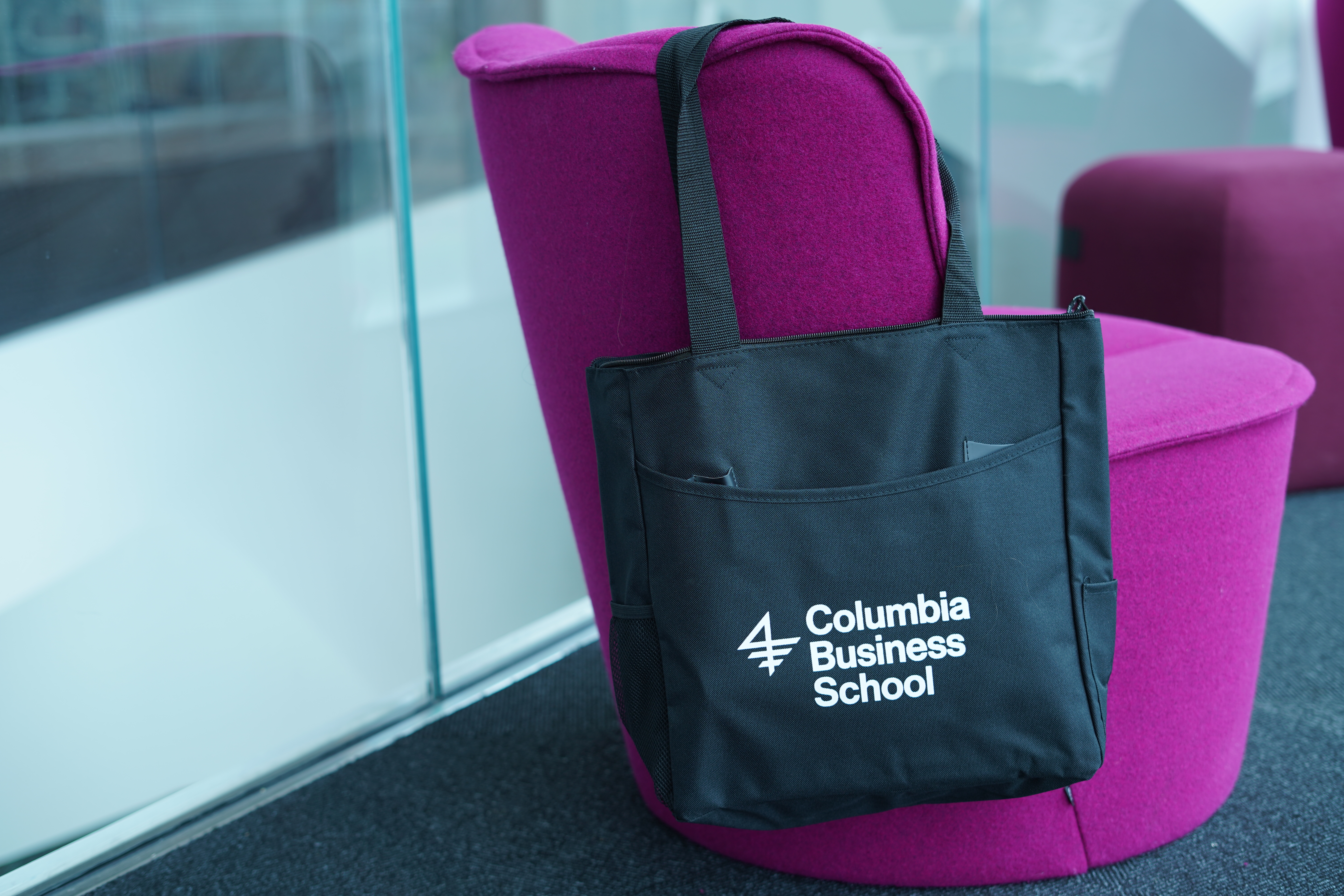A CBS-branded tote bag is slung over the back of a fuschia easy chair