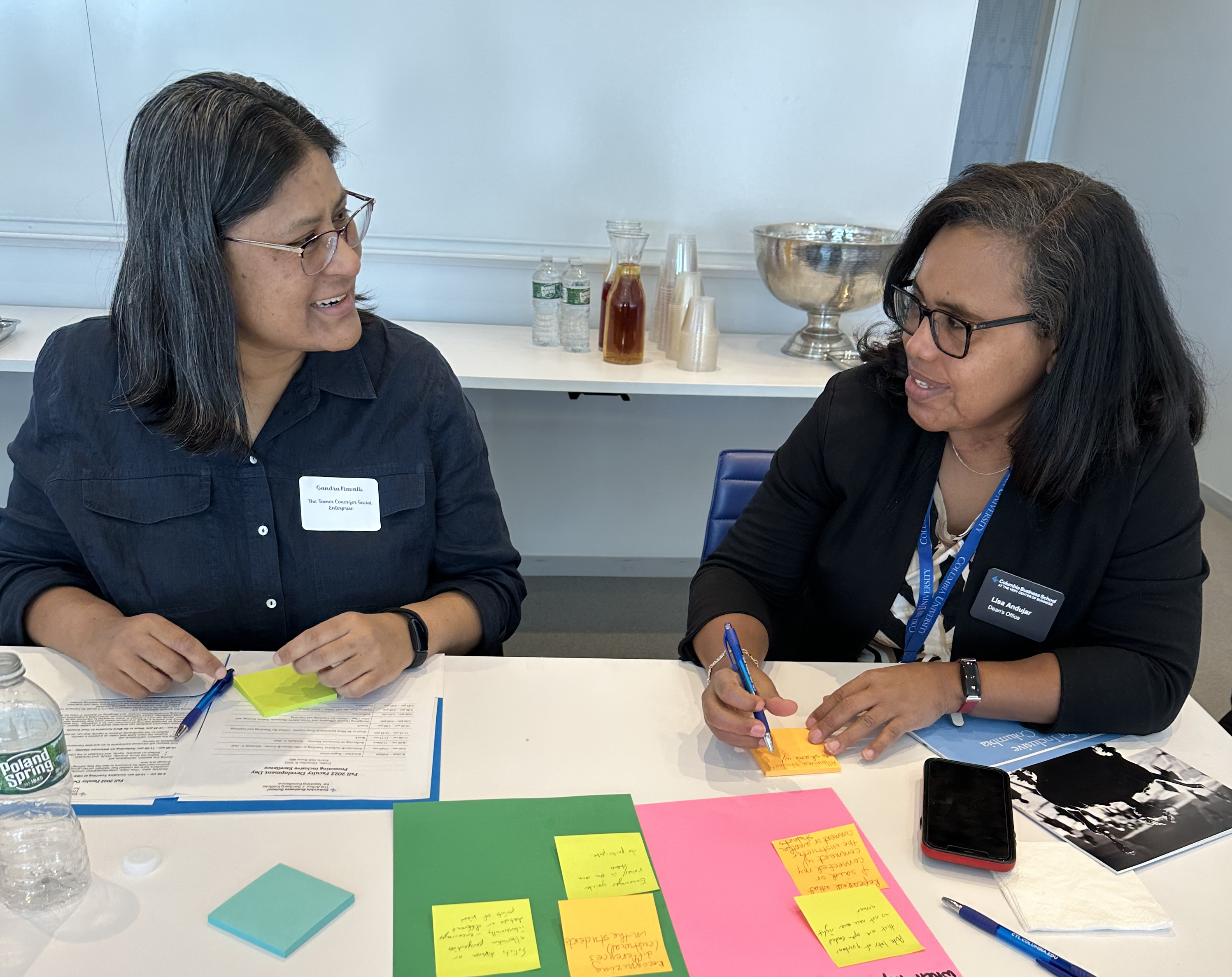 Two people sitting at a table working on a project, smiling at each other