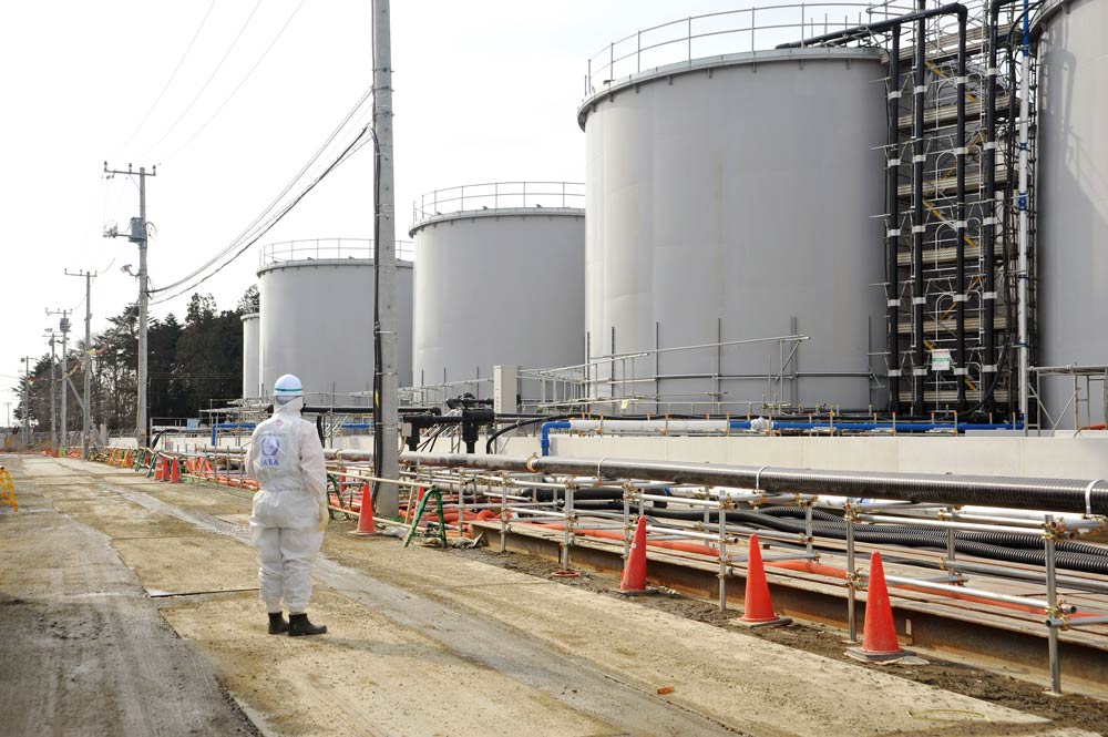 An inspector from the International Atomic Energy Agency examines the exterior of the Fukushima Daiichi Nuclear Power Plant during an inspection of the plant’s decommissioning.