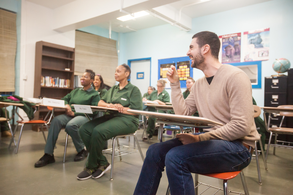 Man sitting at a desk laughing with other students in classroom