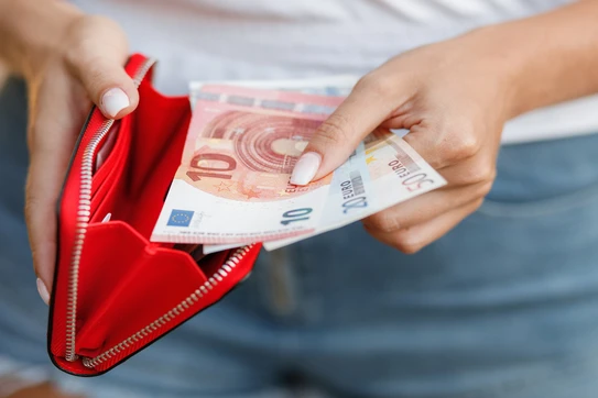 A woman removes 80 euro from a red wallet.