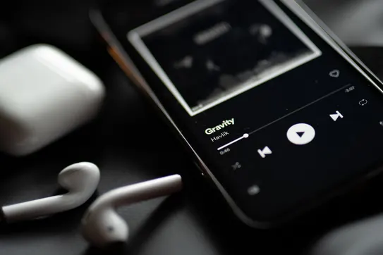 Phone with ear buds and music on the screen