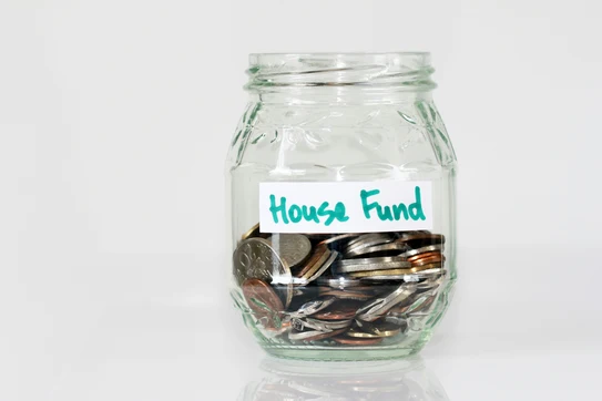 Jar labeled "house fund" with coins in it