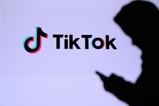 A person using a mobile device next to a TikTok logo