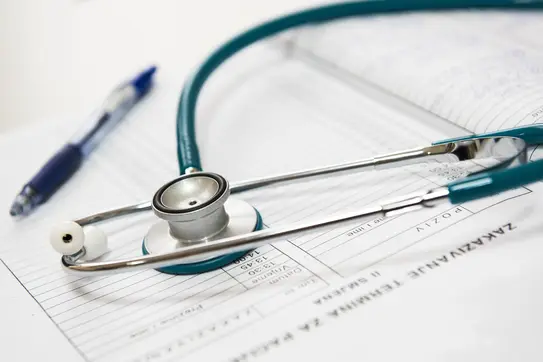 Stethoscope and pen sitting on some paper forms