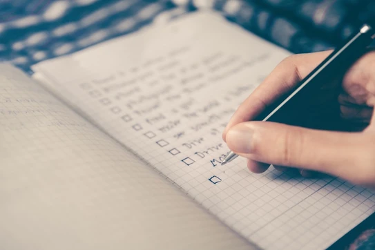 Close-up of a hand writing a to-do list in a notebook