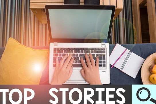 A pair of hands on a laptop next to a pair of fruit and a notepad.